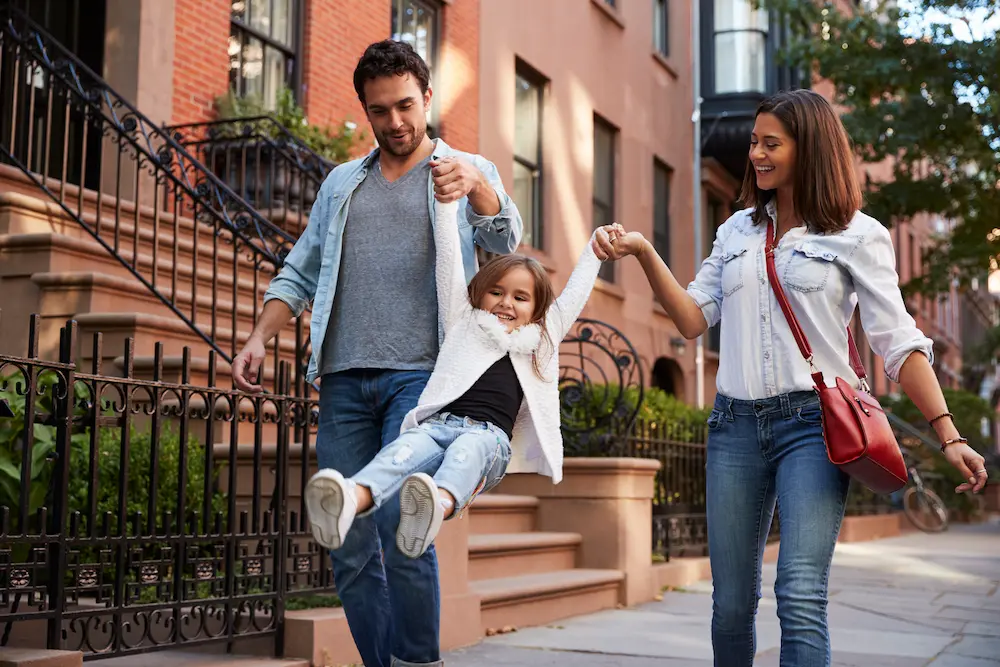 Divorced couple swinging their daughter together.